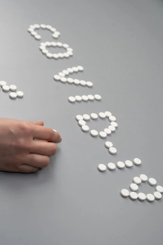 a woman's hand writing the word love with pills on a table, inspired by Cerith Wyn Evans, antipodeans, round-cropped, paul barson, made of nanomaterials, white