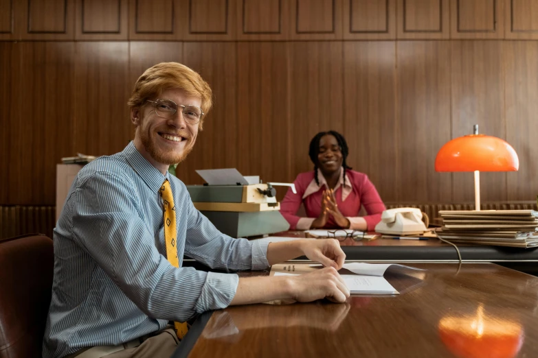 a man and a woman sitting at a table, trending on reddit, background 1970s office, looks like domhnall gleeson, high quality photo, librarian