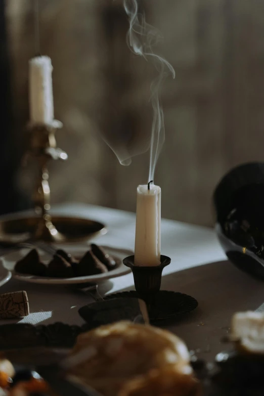 a candle sitting on top of a table next to a plate of food, baroque, ghostly smoke, chocolate, mid shot, wax