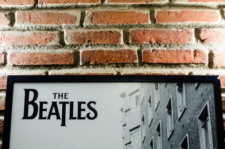 a picture of the beatles hanging on a brick wall, an album cover, by Gavin Hamilton, pexels contest winner, framed poster, closeup - view, foto realista, restaurant menu photo