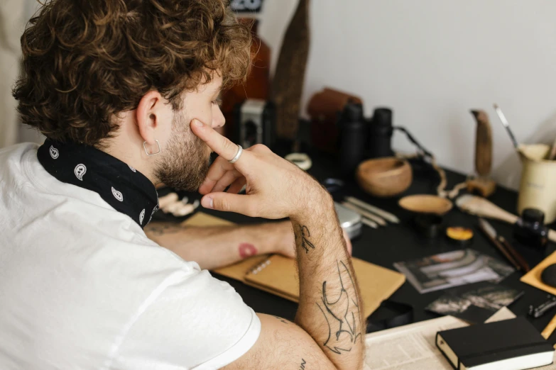 a man sitting at a desk in front of a computer, a tattoo, by Adam Marczyński, trending on pexels, arbeitsrat für kunst, handcrafted, sculptor, sharpie, thoughtful )