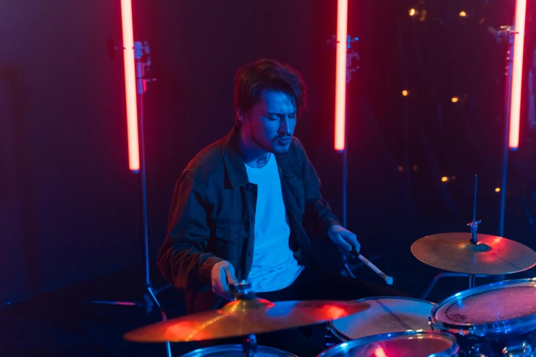 a man that is sitting in front of a drum set, profile image, lights, rectangle, indoor scene