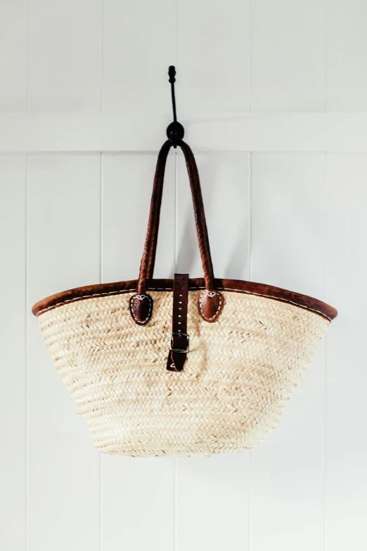 a wicker basket hanging on a wall, by Helen Stevenson, pexels, arabesque, leather straps, high key detailed, arched back, really long