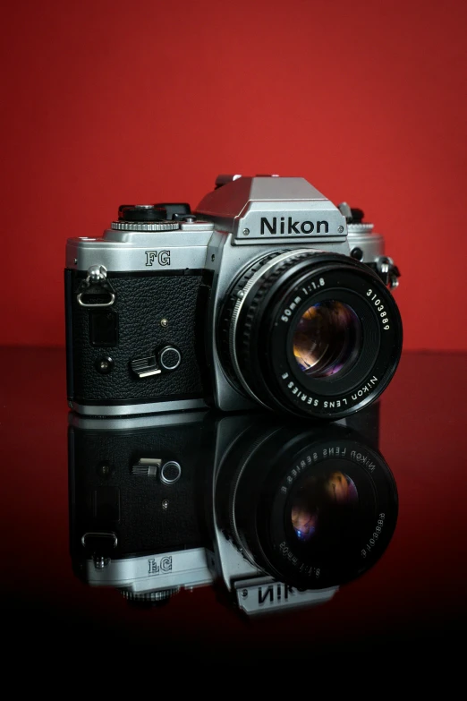 a silver camera sitting on top of a black table, a picture, by Jim Nelson, high detailed photography red, nikkon, on a pale background, icon