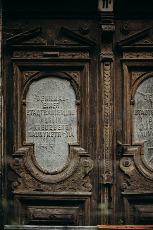 a bench sitting in front of a wooden door, an album cover, by Kristian Zahrtmann, pexels contest winner, intricate stone carvings, inside the sepulchre, with names, old signs