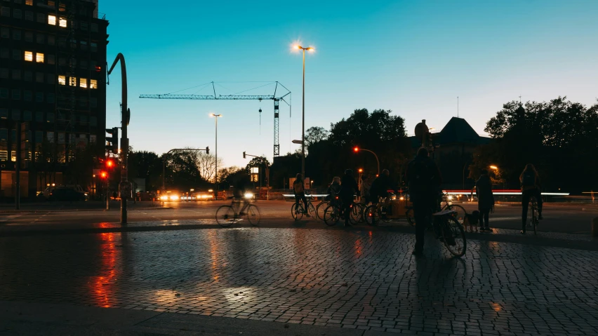 a group of people riding bikes down a street, by Jesper Knudsen, unsplash contest winner, streetlamps with orange light, in a square, construction, calm evening