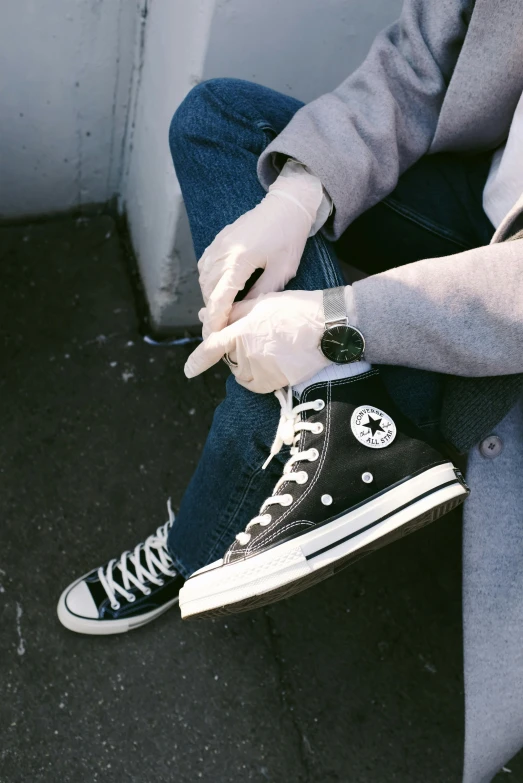 a person sitting on the ground smoking a cigarette, a black and white photo, trending on pexels, wearing red converse shoes, wears a watch, wearing jeans and a black hoodie, lo fi colors