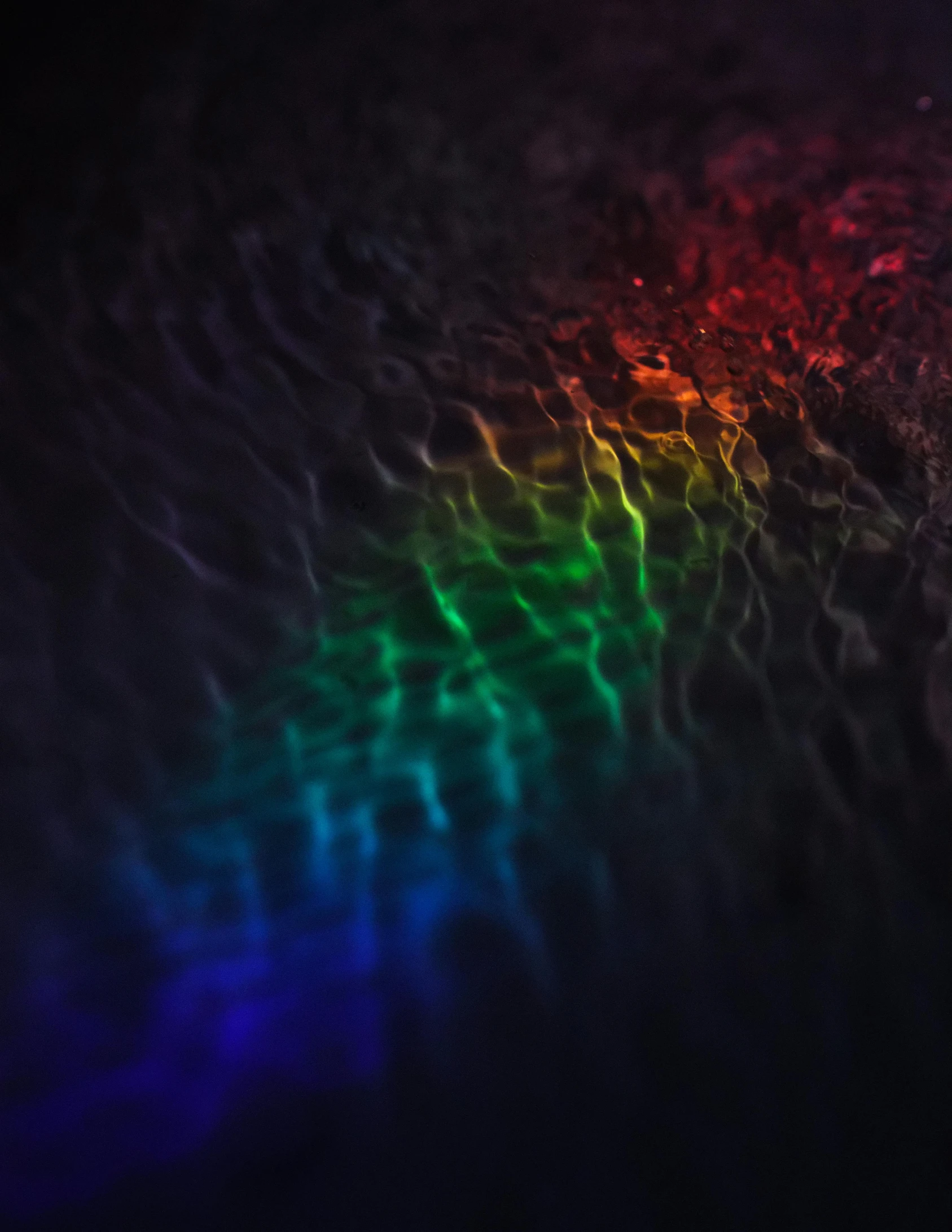 a close up of a rainbow colored light, an album cover, unsplash, water caustics, dark and moody colors, lgbtq, wavy water