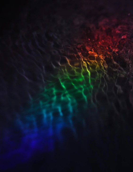 a close up of a rainbow colored light, an album cover, unsplash, water caustics, dark and moody colors, lgbtq, wavy water