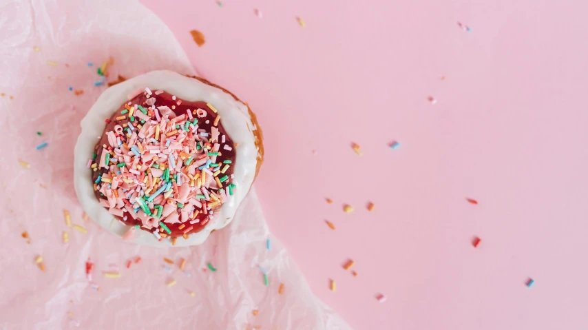 a doughnut with sprinkles on a pink surface, by Emma Andijewska, trending on unsplash, background image, cakes, red and white color theme, 15081959 21121991 01012000 4k