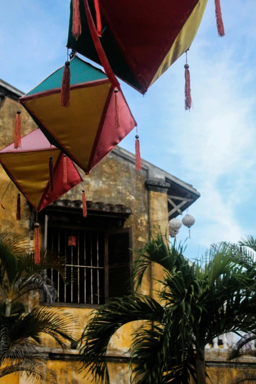 a group of kites hanging from the side of a building, by Ruth Jên, historical setting, dim lantern, phong shaded, seen from outside