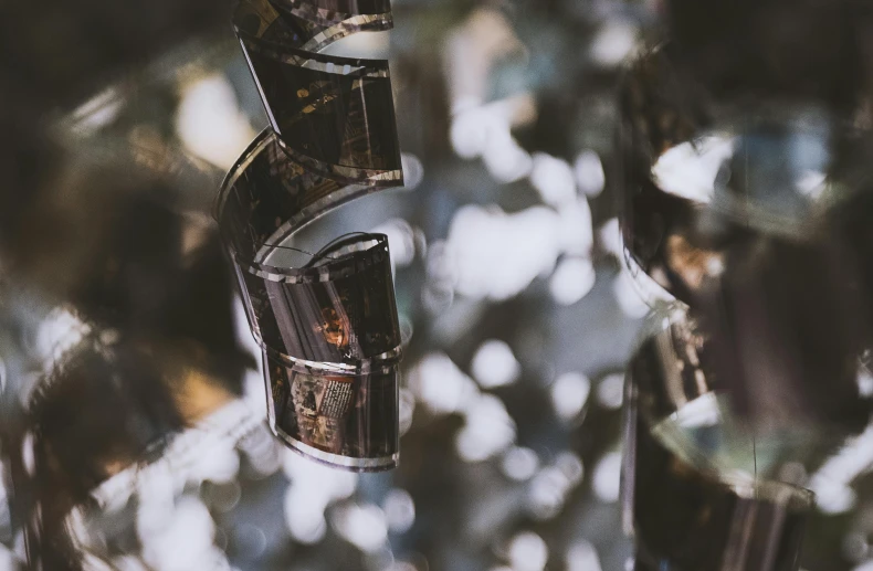 a close up of a metal object with a tree in the background, a microscopic photo, by Emma Andijewska, unsplash contest winner, crystal cubism, scattered glass shards, abstract mirrors, old film, lights on