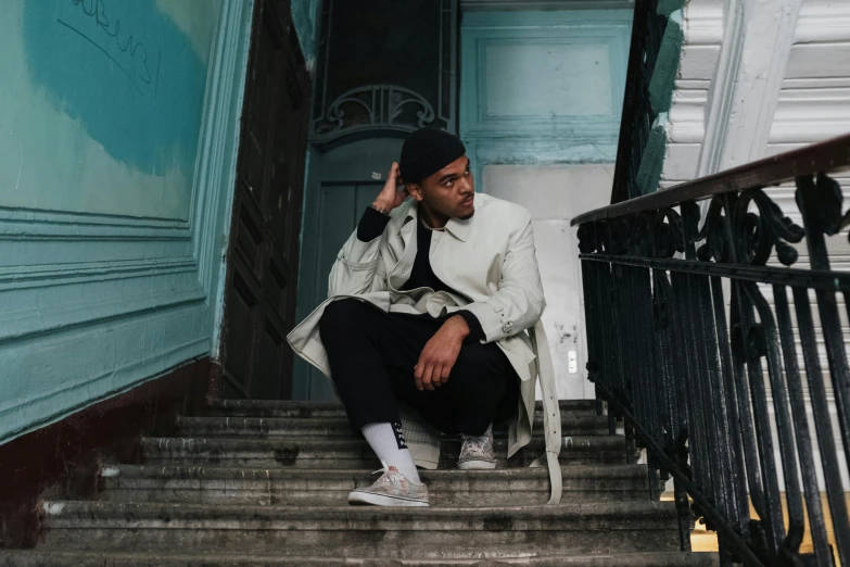 a man sitting on a set of stairs talking on a cell phone, an album cover, by Sebastian Vrancx, pexels contest winner, wearing trenchcoat, chappie in an adidas track suit, confident pose, ariel perez