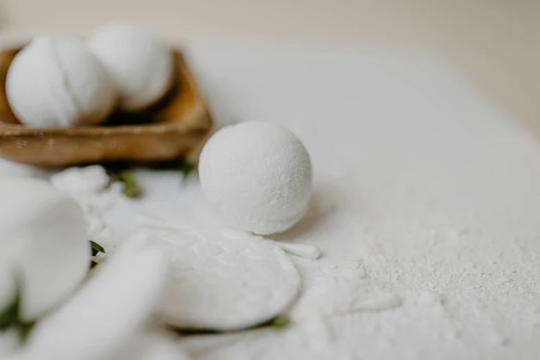 a bunch of white balls sitting on top of a table, covered in white flour, ecommerce photograph, bath, white petal