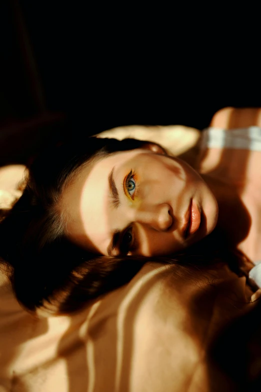 a woman laying on a bed with a remote in her hand, inspired by Elsa Bleda, trending on pexels, photorealism, glowing yellow face, a portrait of a blue eye girl, autochrome, golden light