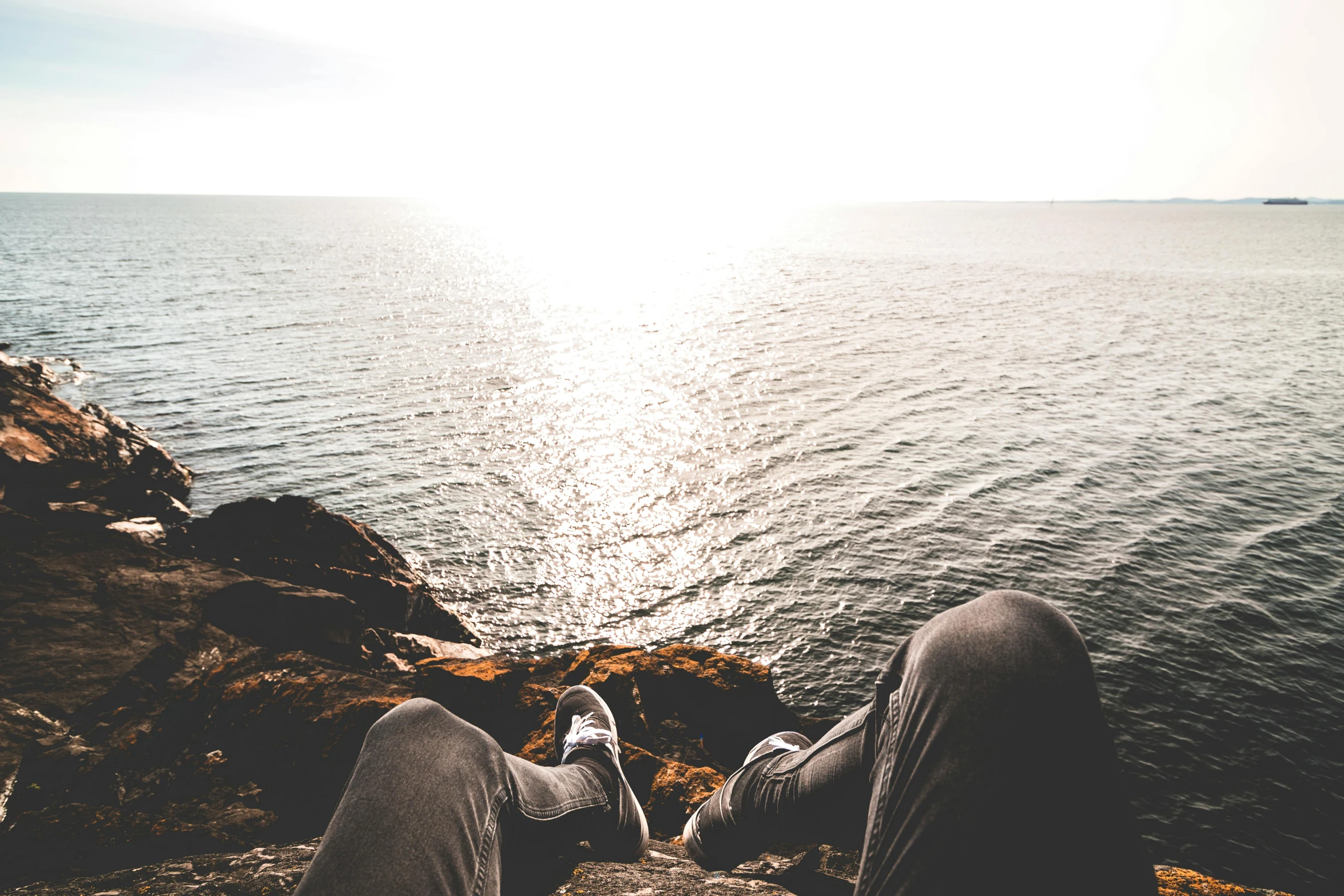 a person sitting on a rock next to a body of water, trending on pexels, happening, sun overhead, view of sea, resting, casually dressed