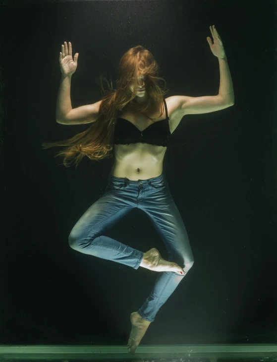 a woman that is standing in the water, a hologram, by Elizabeth Polunin, ( ( ( wearing jeans ) ) ), maiden with copper hair, ultra realistic photograph, acrobatic