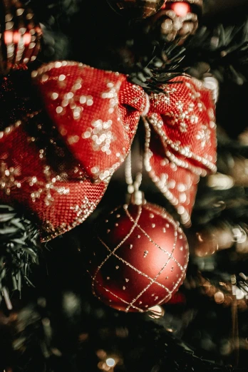 a close up of a christmas tree with ornaments, thick bow, crimson themed, thumbnail, cosy