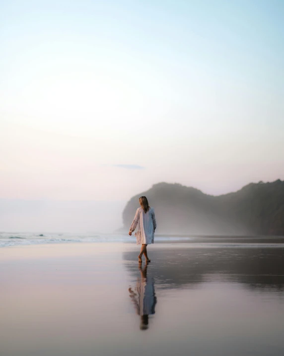 a woman walking on a beach holding a surfboard, pexels contest winner, wearing a velvet robe, abel tasman, soft reflections, dressed in white robes