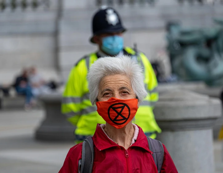 a woman wearing a face mask with a symbol painted on it, ax, british, environmental, 2019 trending photo