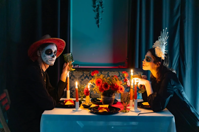 a couple of people that are sitting at a table, by Julia Pishtar, pexels contest winner, vanitas, dia de los muertos makeup, dinner table, square, seasonal
