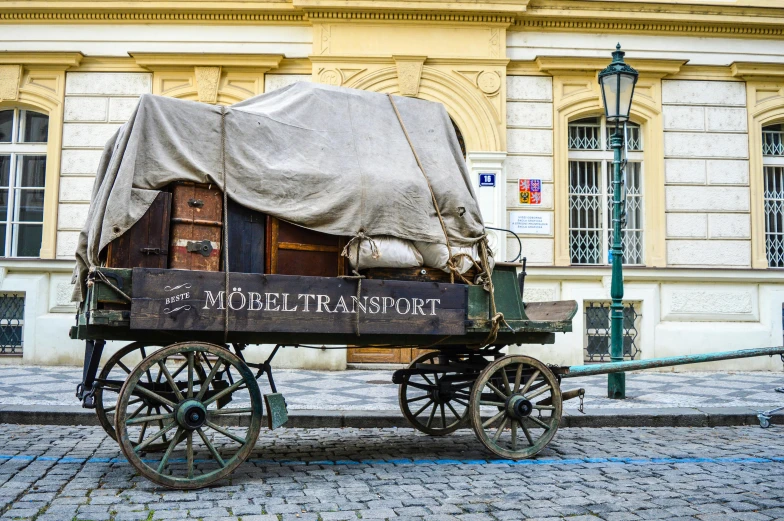 a covered wagon is parked in front of a building, by Adam Szentpétery, pexels contest winner, art nouveau, square, slovakia, slide show, 🚿🗝📝