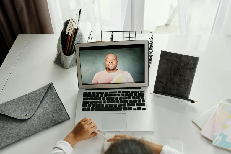 a person sitting at a desk in front of a laptop computer, trending on pexels, video art, huell babineaux, teacher, lizzo, wide high angle view