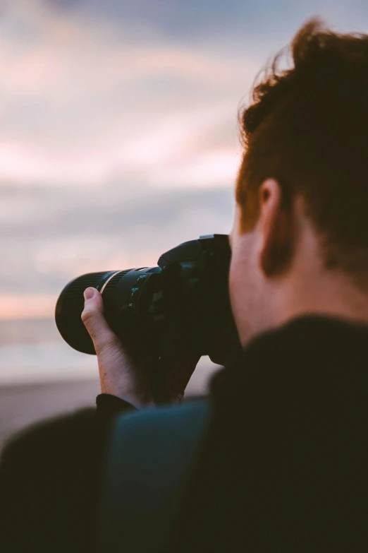 a man taking a picture of the ocean with a camera, by Carey Morris, pexels contest winner, bokeh. rule of thirds, headshot, sunset photo, panoramic photography