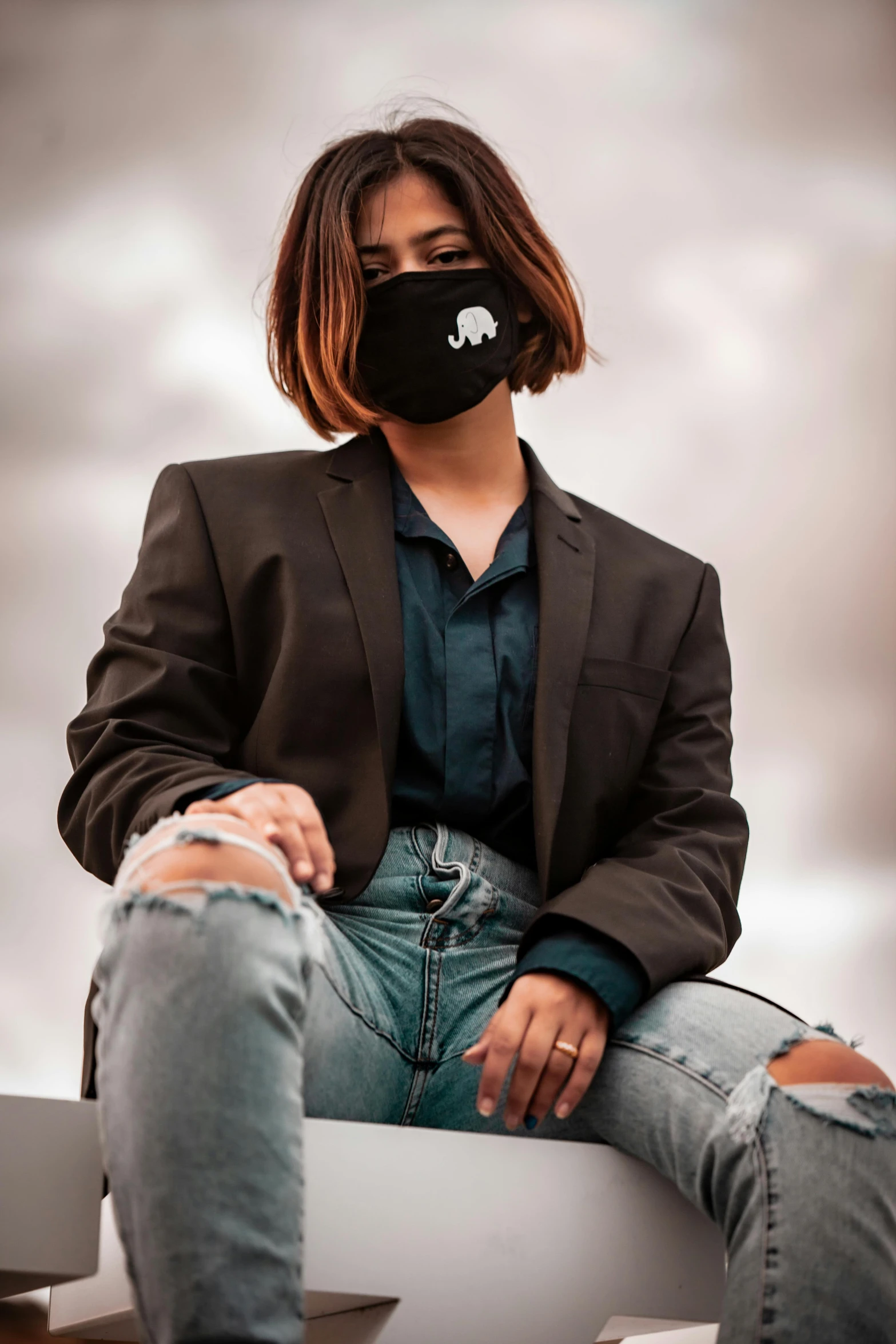 a woman wearing a face mask sitting on a bench, an album cover, trending on pexels, wearing a black blazer, techwear look and clothes, denim, sitting in a fluffy cloud