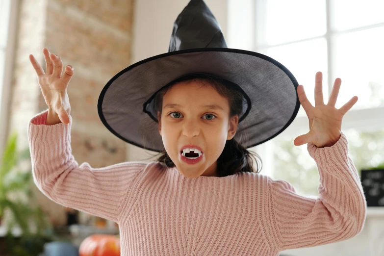 a little girl wearing a witch hat making a funny face, pexels, hurufiyya, shark teeth, transforming into werewolf, grey, seasonal