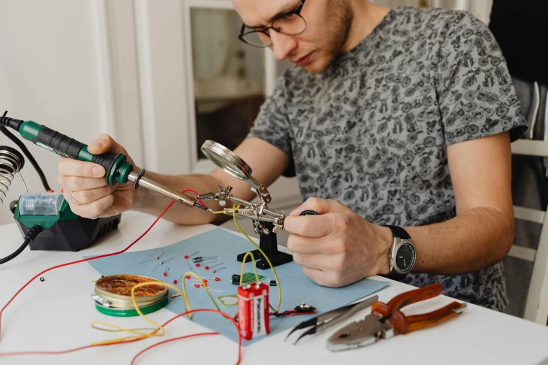 a man sitting at a table working on a project, pexels, arbeitsrat für kunst, capacitors and coils inside, having fun, with electric arc devices, avatar image