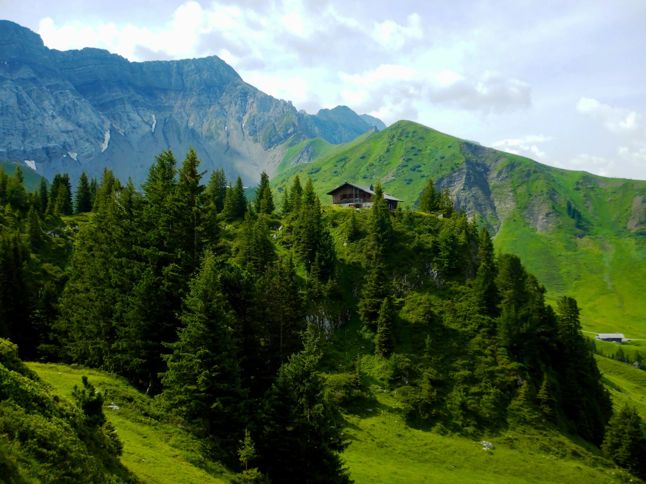 a house sitting on top of a lush green hillside, by Werner Andermatt, pexels contest winner, chalet, hill with trees, suzanne engelberg, high elevation