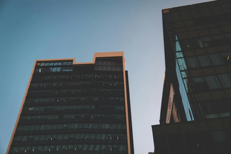 a couple of tall buildings next to each other, a photo, unsplash, modernism, faded glow, tall obsidian architecture, low angle view, modern high sharpness photo