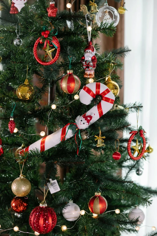 a decorated christmas tree in a living room, candy canes, tissue ornament, medium, on a tree