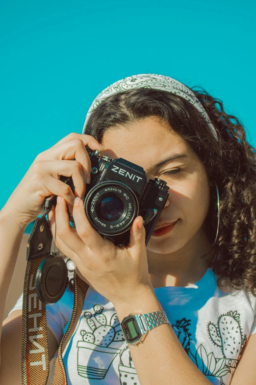 a woman taking a picture with a camera, pexels contest winner, with a blue background, portrait sophie mudd, blue sky, vintage soft grainy