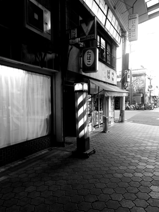 a black and white photo of a city street, a black and white photo, by Tsubasa Nakai, shop front, morning sun, けもの, iphone capture