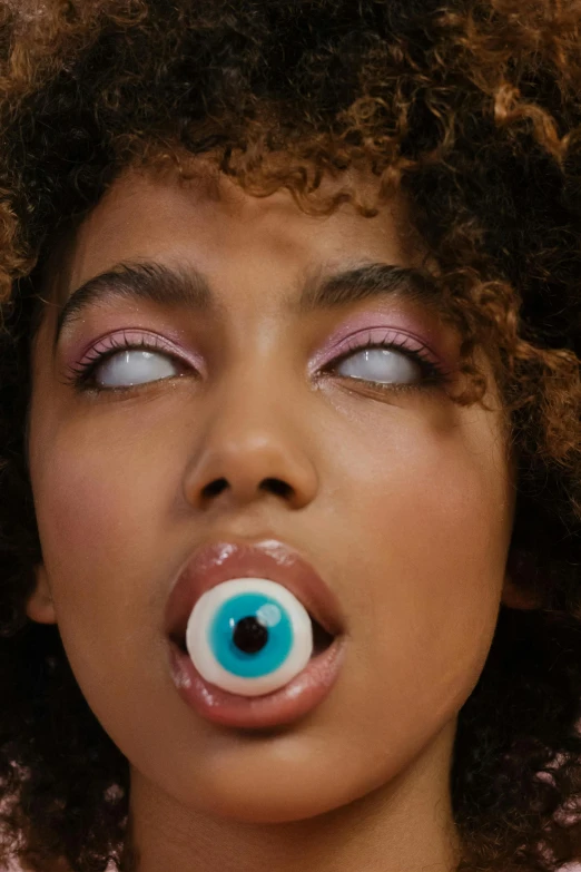 a woman with an eyeball in her mouth, an album cover, inspired by David LaChapelle, trending on pexels, mixed race, button eyes, lollipop, halloween