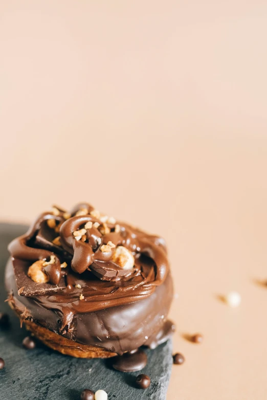 a chocolate cupcake sitting on top of a black plate, by Andries Stock, trending on pexels, hurufiyya, rocky roads, on a pale background, made of glazed, thumbnail