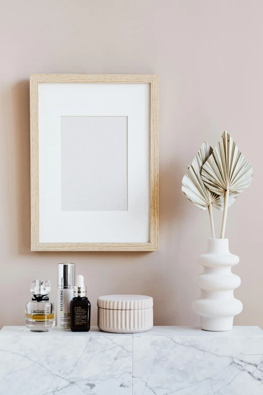 a picture frame sitting on top of a marble counter, poster art, featured on pinterest, visual art, skincare, light wood, soft lighting colors scheme, vases and bottles