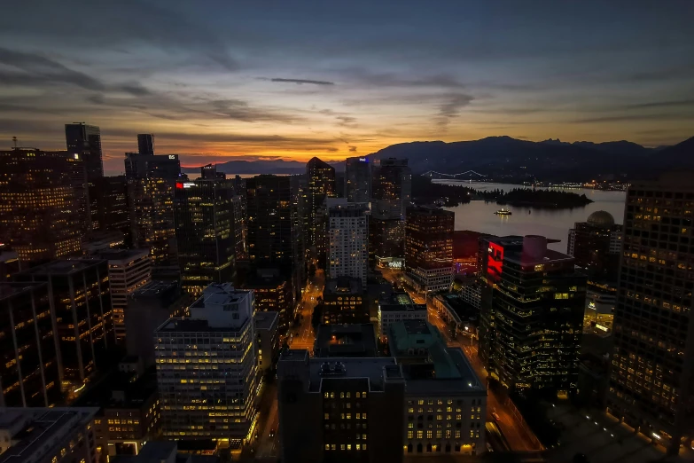 a view of a city at night from the top of a building, by Chris Rallis, pexels contest winner, vancouver school, sunset photo, slide show