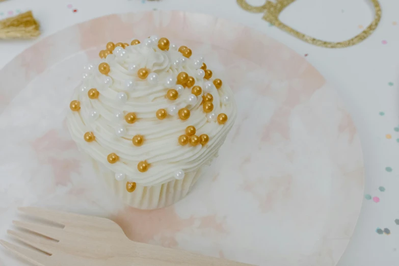 a cupcake sitting on top of a white plate, trending on unsplash, gold and pearls, parchment paper, background image, miniature product photo