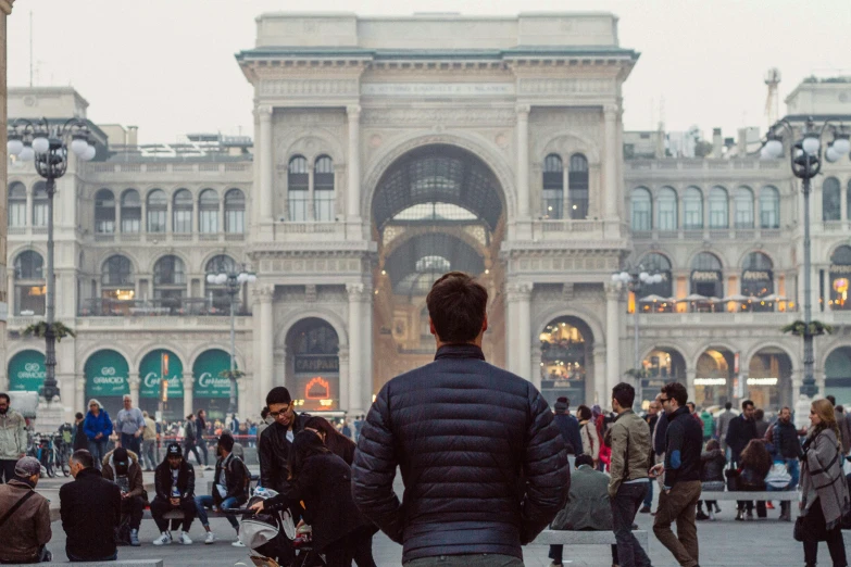 a man standing in front of a crowd of people, by Giuseppe Avanzi, pexels contest winner, renaissance, big arches in the back, milan schere, promo image, in a square