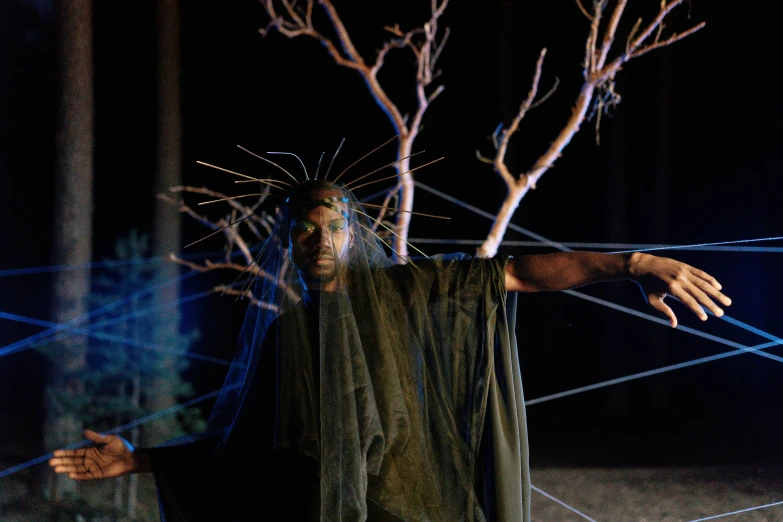 a man that is standing next to a tree, dressed as an oracle, production still, black jesus, songlines