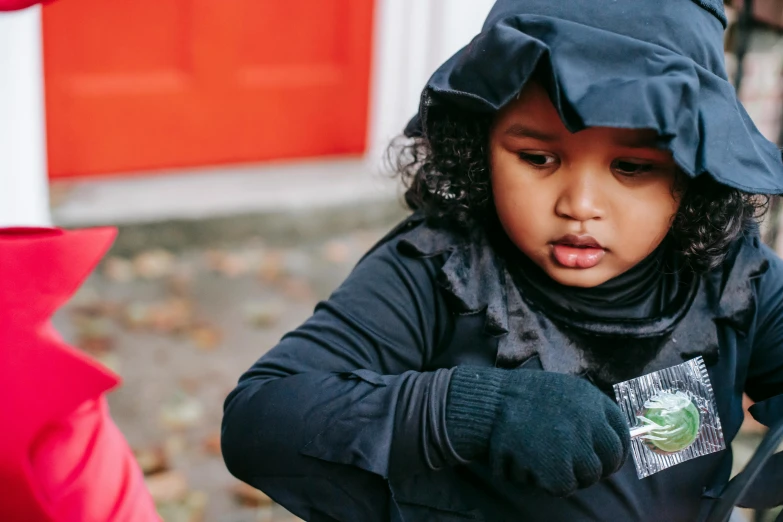 a little girl standing next to a red fire hydrant, a portrait, by Helen Stevenson, pexels contest winner, face is wrapped in a black scarf, an ewok eating a lollipop, outfit: cop, riyahd cassiem