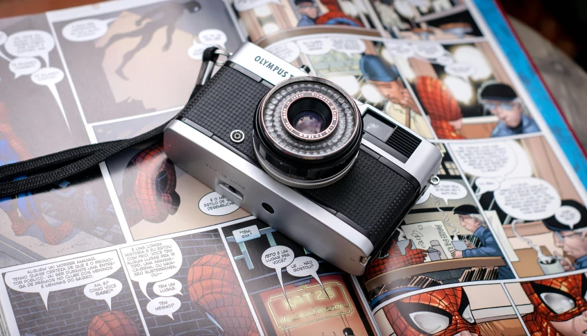 a camera sitting on top of a book, inspired by Joe Shuster, unsplash, photorealism, marvel comic, cosplay journal cover, beautiful 2000s phone-camera, 38mm photograhpy