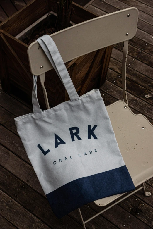 a blue and white tote bag sitting on a chair, halo ark, lakeside, clean logo, commercial banner