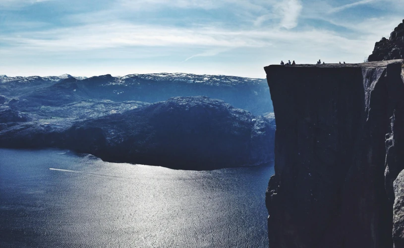 a group of people standing on top of a cliff, by Jesper Knudsen, pexels contest winner, hurufiyya, snowy fjord, towering high up over your view, thumbnail, blue