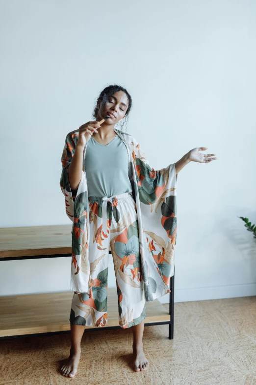 a woman standing in front of a white wall, inspired by Sawa Sekkyō, unsplash, ukiyo-e, wearing pajamas, waving robe movement, at home, lena oxton