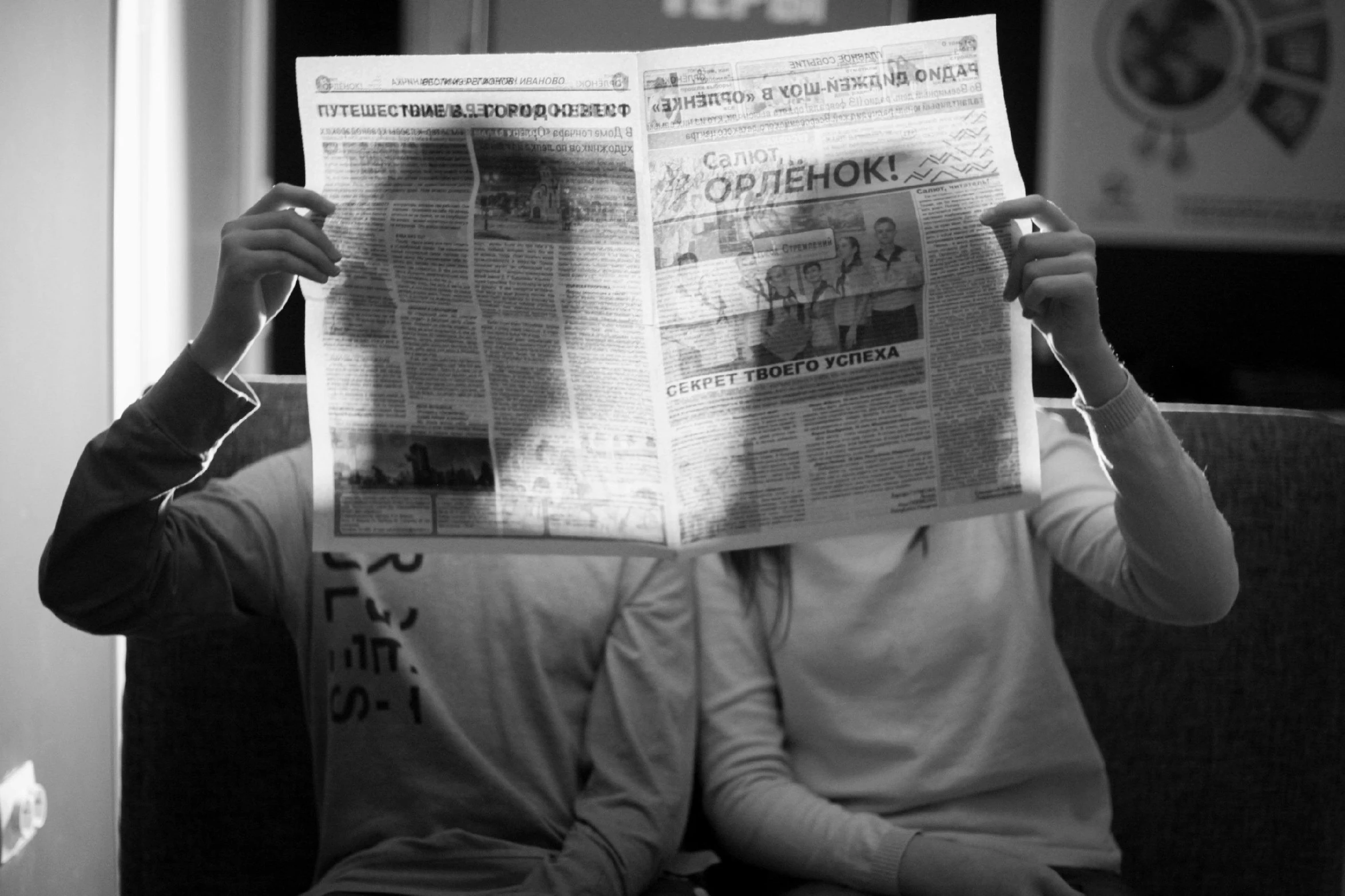 a man sitting on a couch reading a newspaper, a black and white photo, by Stefan Gierowski, conjoined twins, ekaterina, 000 — википедия, in love