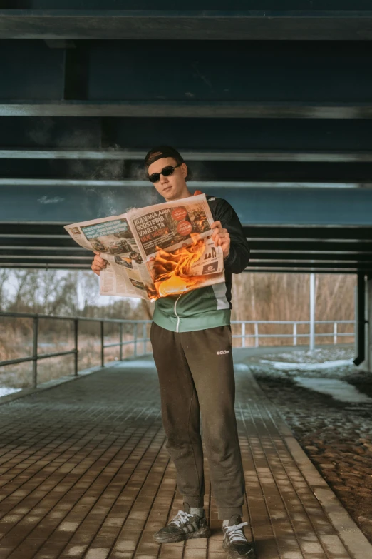 a man standing under a bridge reading a newspaper, an album cover, by Sebastian Spreng, pexels contest winner, casting fire spell, bad bunny, valeriy vegera, teddy fresh
